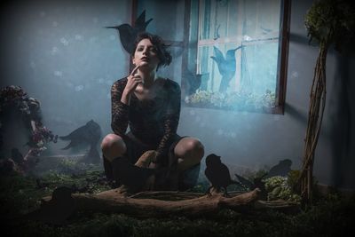 Portrait of young woman with spooky make-up sitting at home during halloween