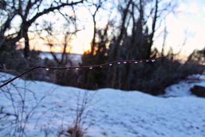 Snow on land against sky during sunset