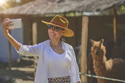 Young tourist takes selfies of alpacas and llamas on the farm. farming industry in peru. 