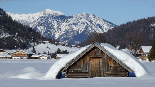 Snow covered landscape and mountains against sky