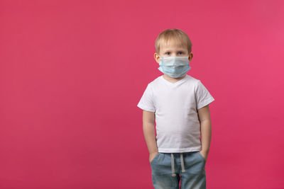 A blond european-looking child boy stands in a medical mask from a coronavirus and looking. 