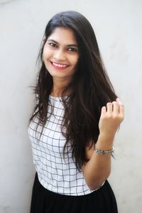 Portrait of smiling woman standing against wall