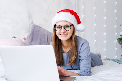 Woman in santa hat playing on laptop at christmas online shopping for holidays