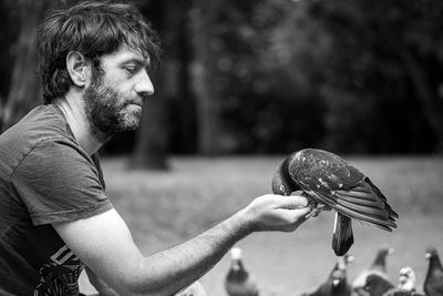 Side view of man feeding bird