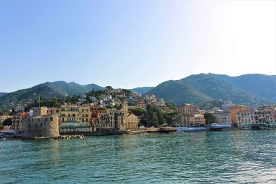 Scenic view of river by buildings against clear sky