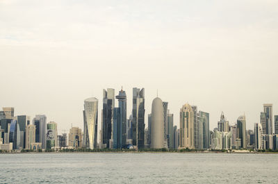 Sea by buildings against sky in city