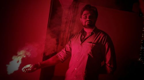 Portrait of man standing in red fire