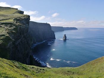 Scenic view of sea by cliff against sky