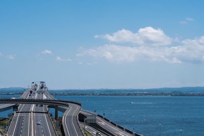 Bridge over sea against cloudy sky