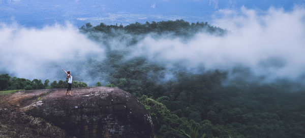 Rear view of man standing on mountain against sky