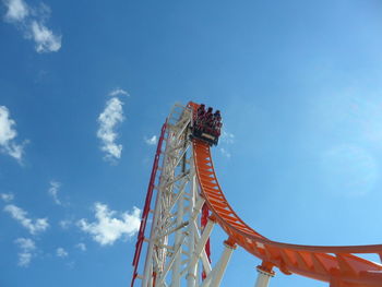 Low angle view of rollercoaster against blue sky