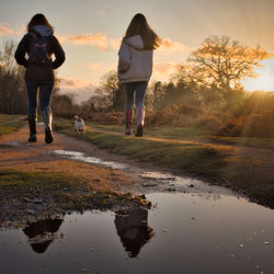 Rear view of two women walking on riverbank