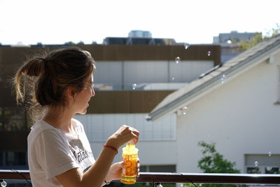 Side view of woman playing with bubble wand