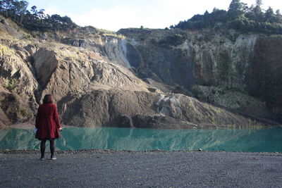 Rear view of woman looking at rock formation by lake