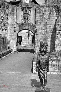 Rear view of woman walking on footpath against building