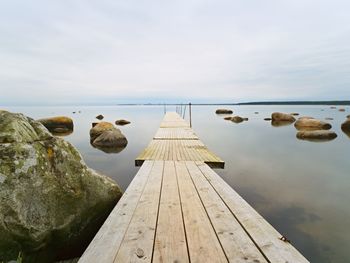 Surface level of wooden pier over sea against sky