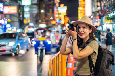 Smiling young woman standing on illuminated city street