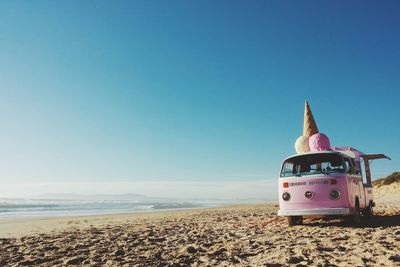Ice cream van on sandy beach against clear blue sky