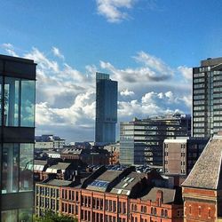 Buildings in city against cloudy sky