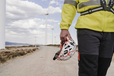 Hand of technician holding helmet at wind farm