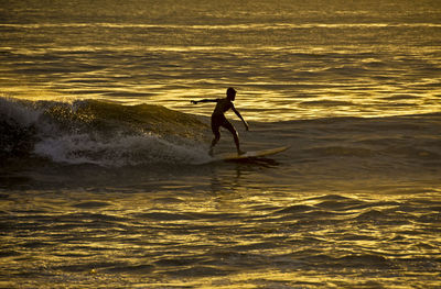 A man plays surfing during high waves on ampenan beach, mataram, west nusa tenggara, 