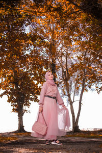 Midsection of woman standing by tree during autumn