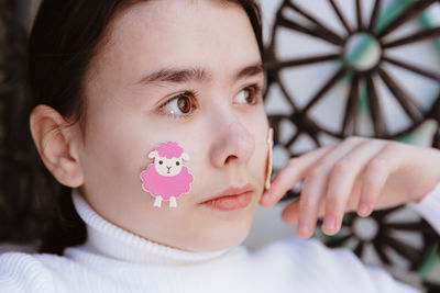 Portrait of a beautiful girl with a lamb sticker on her cheek.
