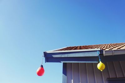 Low angle view of decoration hanging from roof against clear blue sky