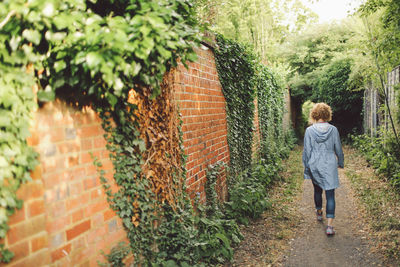 Woman walking next to brick wall