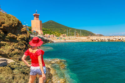 Rear view of woman standing by sea against clear sky