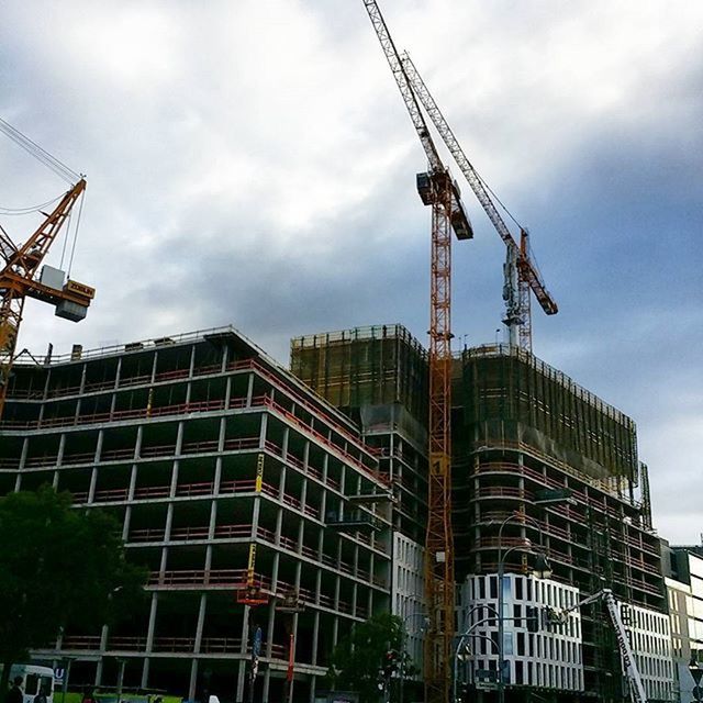 architecture, building exterior, built structure, crane - construction machinery, construction site, sky, development, low angle view, crane, tall - high, cloud - sky, cloudy, construction, industry, tower, fuel and power generation, incomplete, city, construction industry, alternative energy