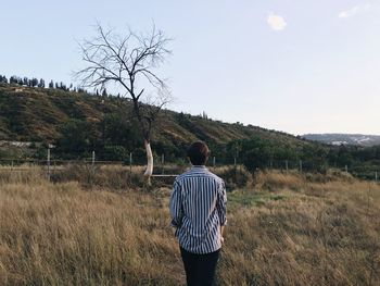 Rear view of person standing on field against sky