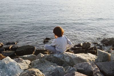 Rear view of man sitting on rocks