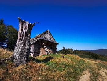 Traditional building on field against clear blue sky