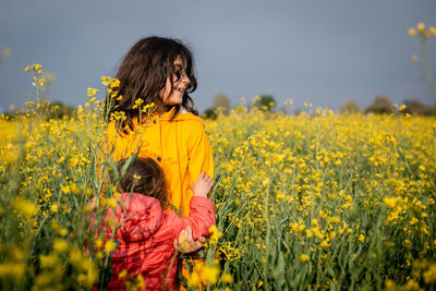 Two children standing in a yellow blooming field