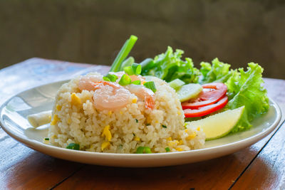 Close up fried rice with shrimp, egg and green onion on white plate.