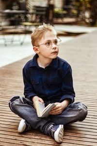 Portrait of boy sitting on footpath