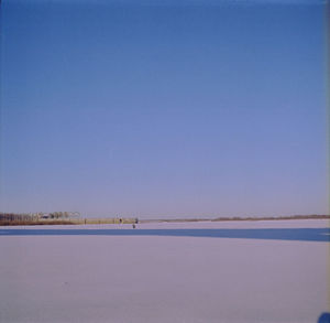 Scenic view of frozen lake against clear blue sky