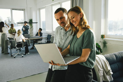 Male and female business professionals discussing over laptop at office