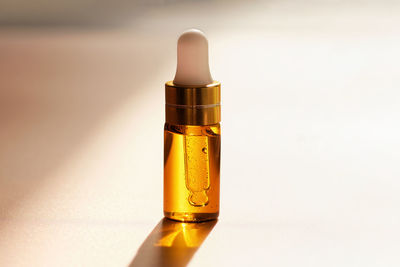 Cosmetic amber glass dropper bottle with oil, serum or fruit peeling in the sunlight on beige 