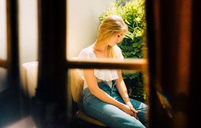 Side view of woman sitting by window