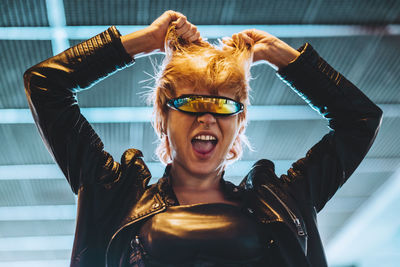 Happy young woman wearing smart glasses with hands in hair