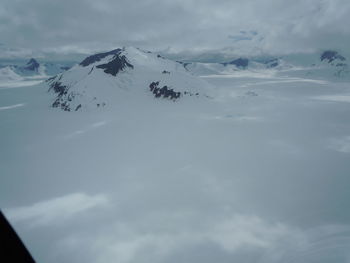 Scenic view of snow covered mountains against cloudy sky