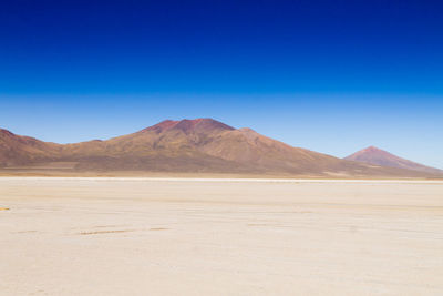 Scenic view of desert against clear blue sky