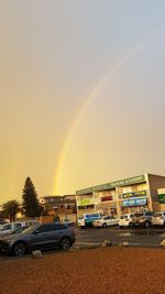 Rainbow over road in city against sky