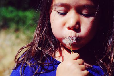 Close-up of cute girl blowing dandelion