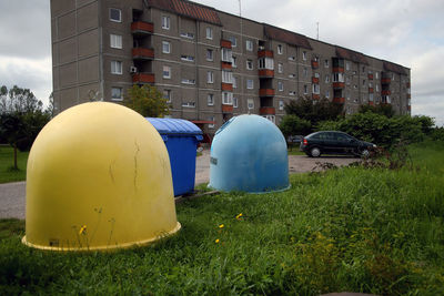 Cars on field by buildings against sky