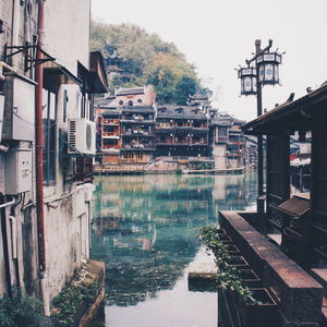 Buildings by lake against sky in city