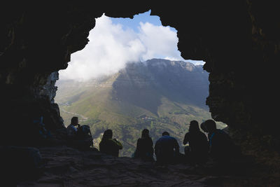 Rear view people sitting in cave opening