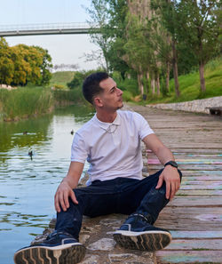 Portrait of young man sitting at lakeshore